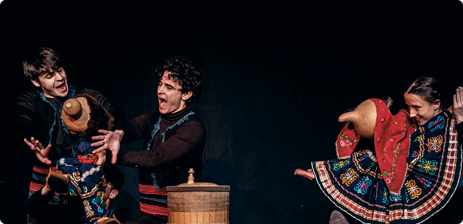 Trzech aktorów ożywia kolorowe, tradycyjne kukiełki na ciemnej scenie