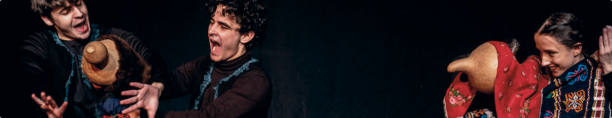 Trzech aktorów ożywia kolorowe, tradycyjne kukiełki na ciemnej scenie